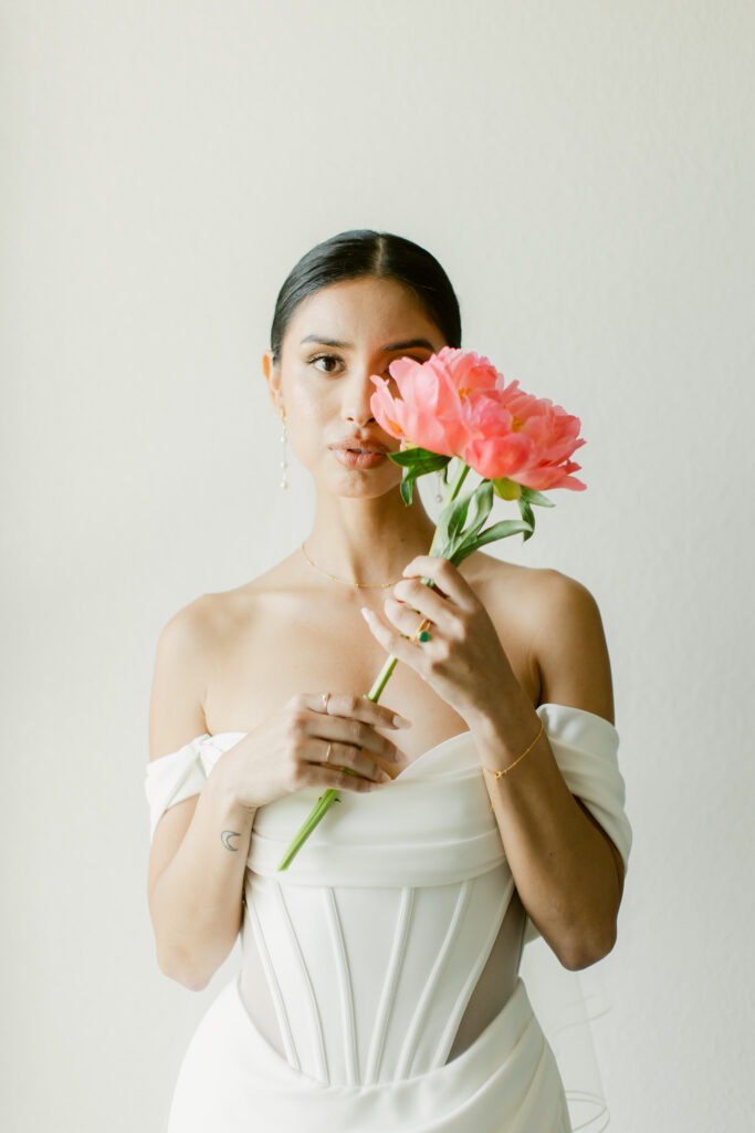Bride in a wedding gown posing with pink floral bouquet for bridal portraits.