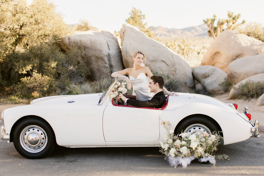 Romantic and editorial wedding portrait of bride and groom in classic car