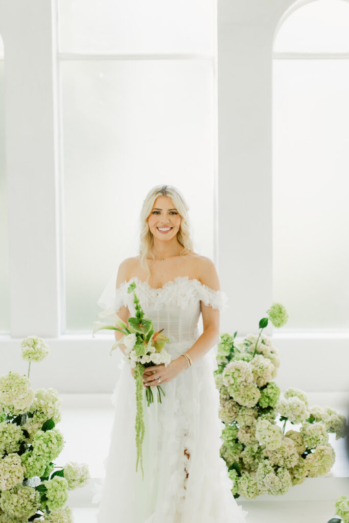 Bride smiling while holding green and white bouquet