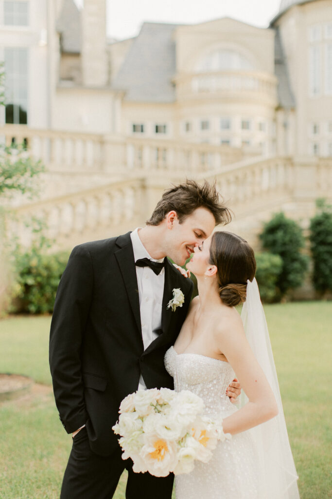 Bride and groom sharing a kiss in a château courtyard at golden hour