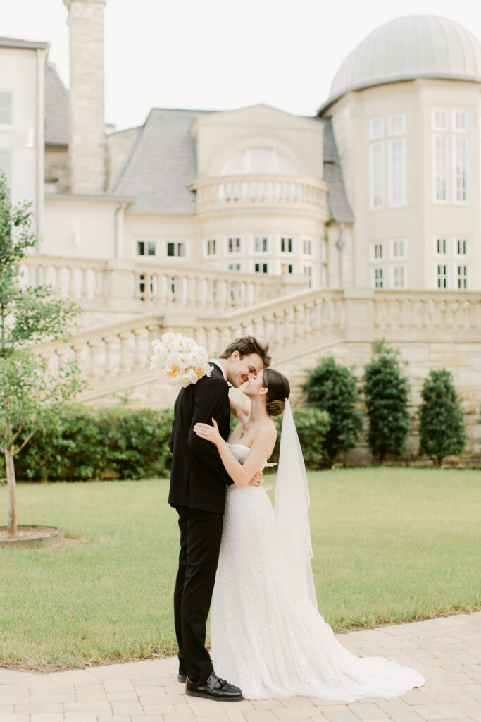 Bride and groom sharing a gentle smile kiss at sunset with château backdrop