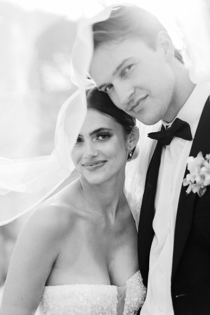 Bride and groom in quiet embrace on château staircase, captured in black and white