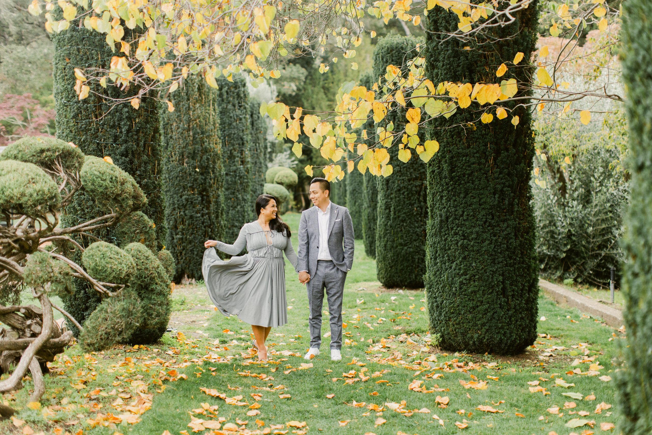 Couple walking hand in hand through fallen leaves at Filoli