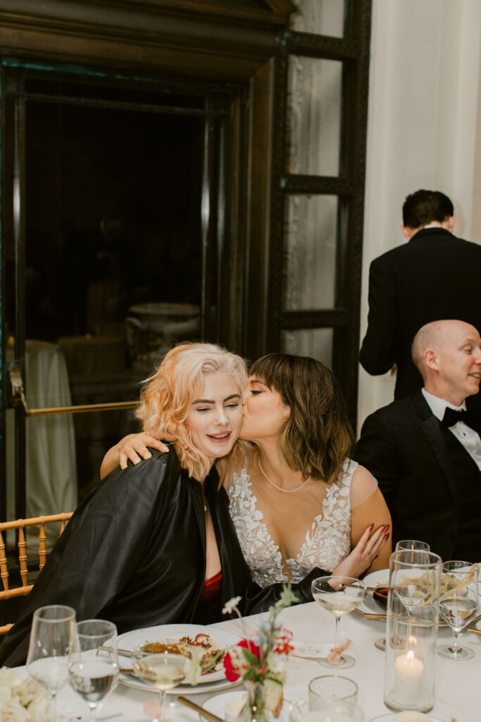 Bride embracing her bridesmaid during Flood Mansion wedding reception