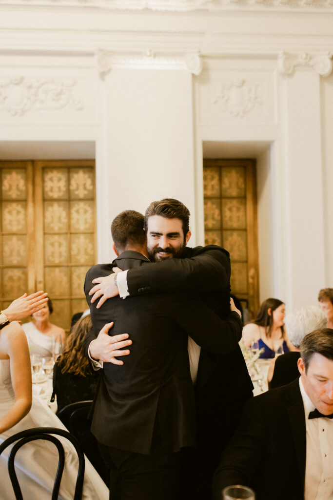 Groom hugging friend during reception