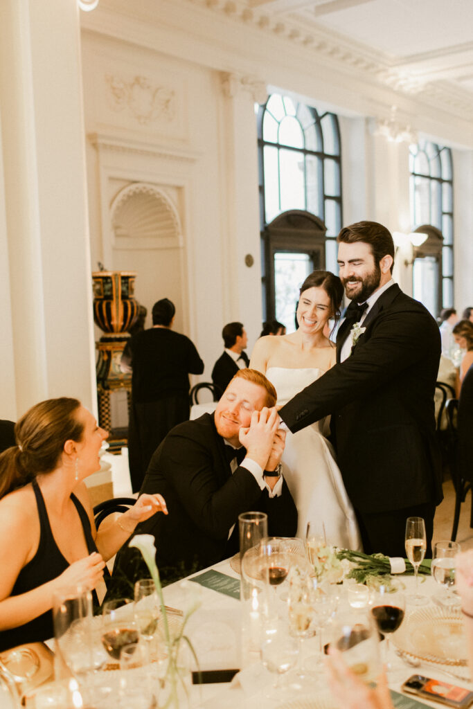 Friend embracing groom during Flood Mansion wedding reception